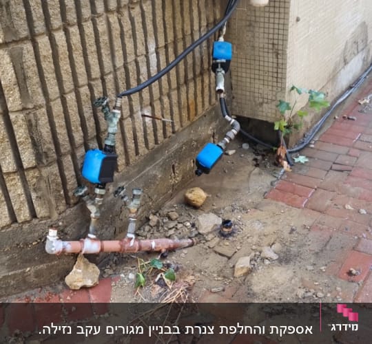 צנרת חיצונית עם ברזים ומחברים על קיר לבנים